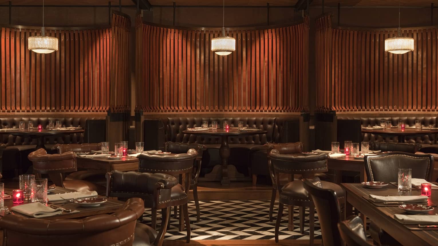 Elena crescent-shaped dark leather booths, leather cocktail chairs and tables, black-and-white tile floor