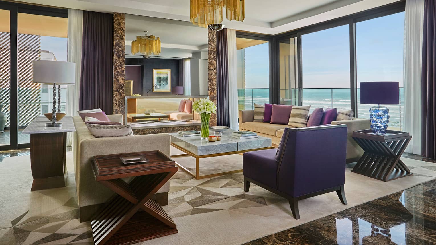 Royal Suite living room with modern sofas, tables, black marble floors, large mirror, chandelier