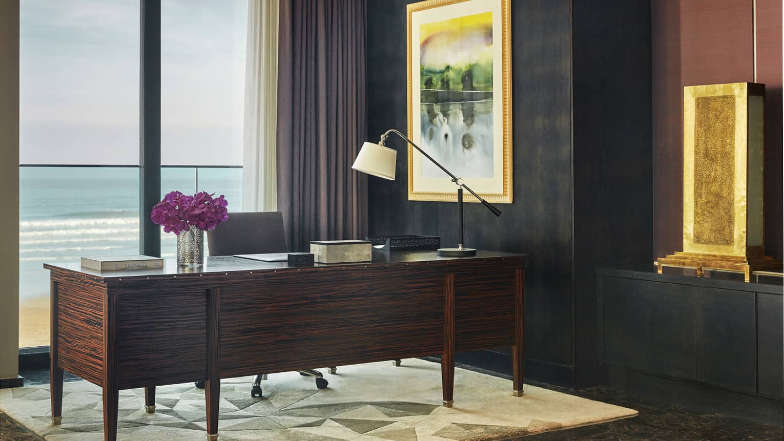 Royal Suite Ocean View office with large executive desk, lamp and purple flowers