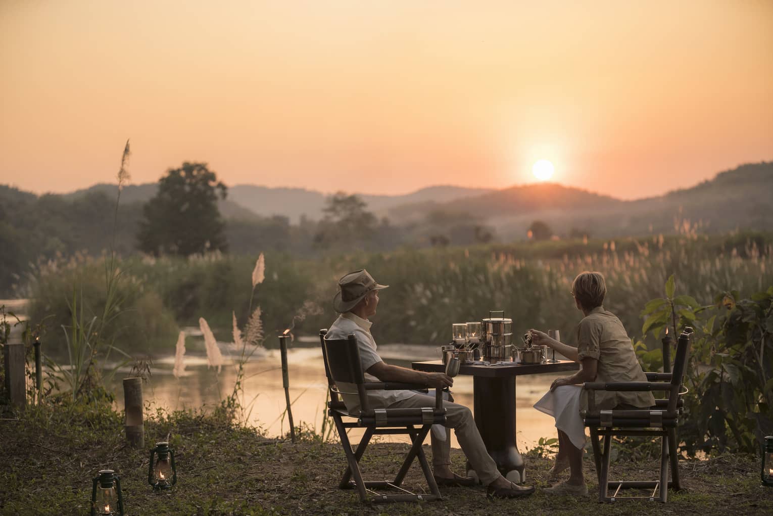 Couple enjoys Camp Bush Dinner along river at sunset