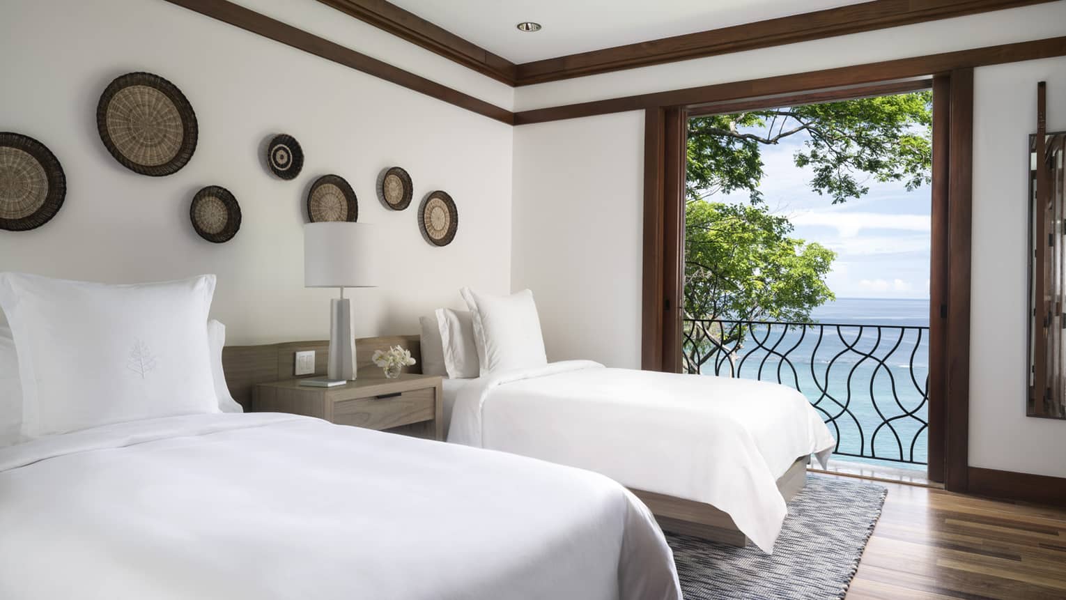 Twin beds with white linens beside open door to iron terrace, ocean views 