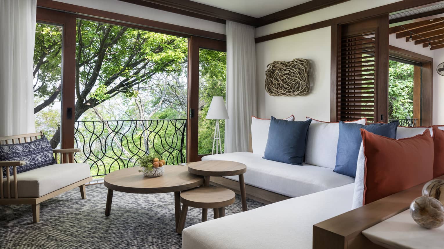 Pacifico Two-Bedroom Resort Residence living room with white L-shaped sofa, three-tiered table by large open wall