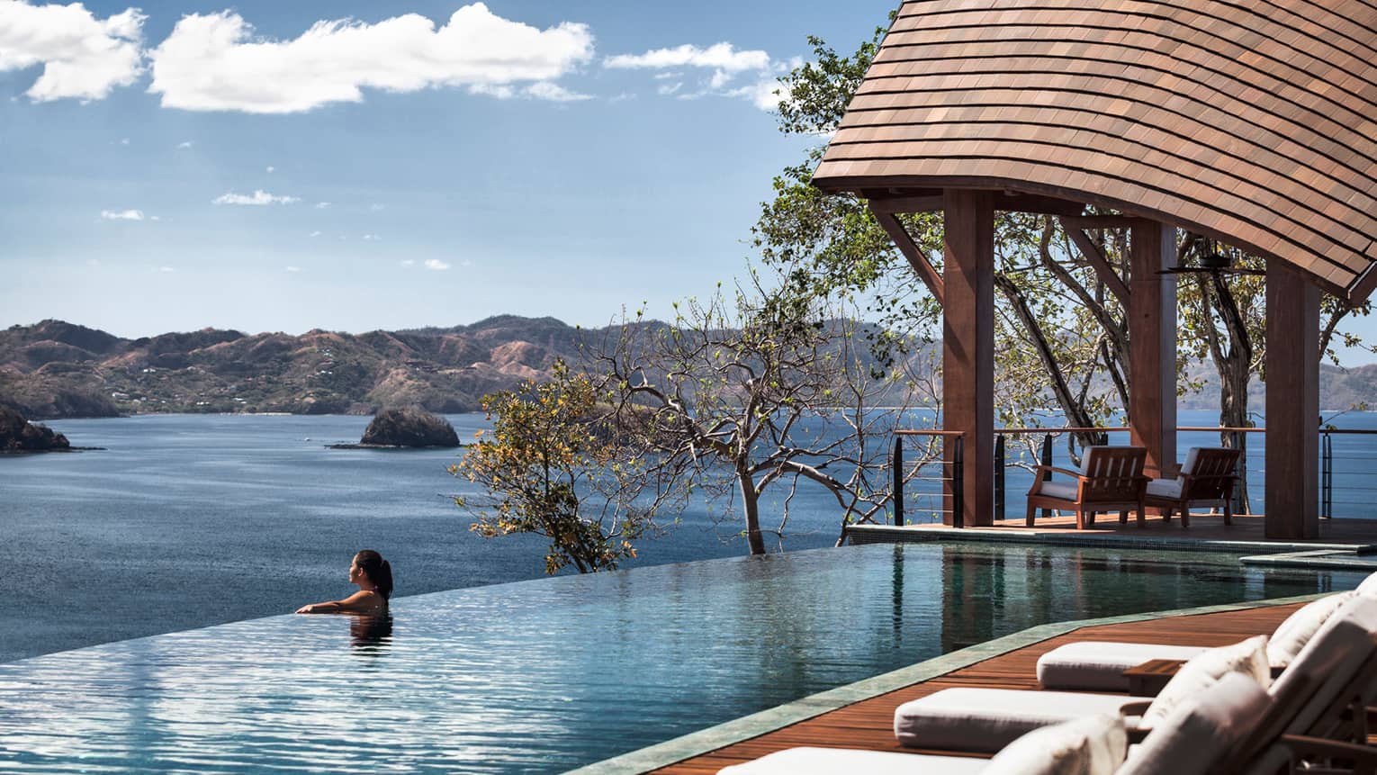 Casa del Cileo Residence Estate patio and wood cabana, woman at edge of infinity pool looking out at ocean