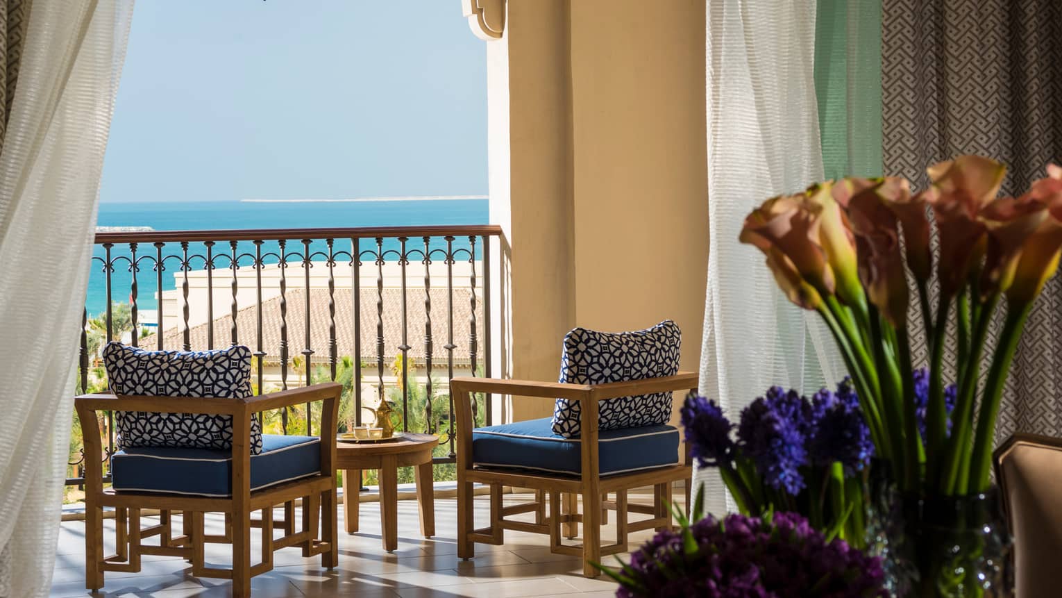 Imperial Suite with blue and purple flowers, sunny balcony with wood furniture, blue cushions
