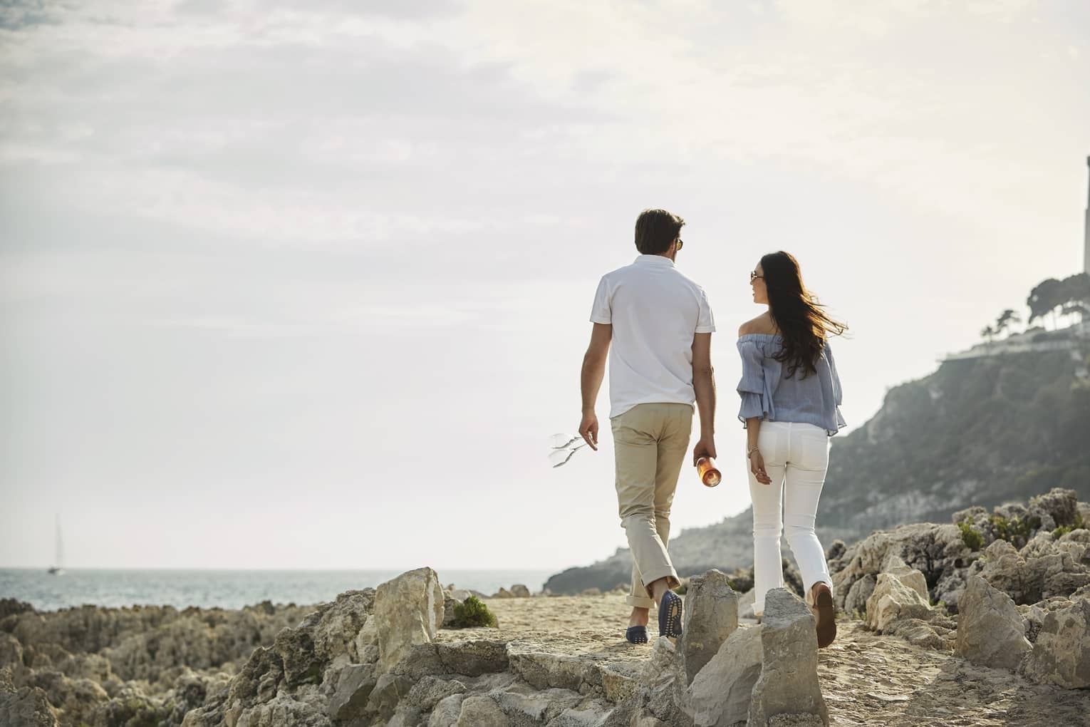 Back of couple walking across rocky trail on Saint-Jean Cap Ferrat Coastal Pathway