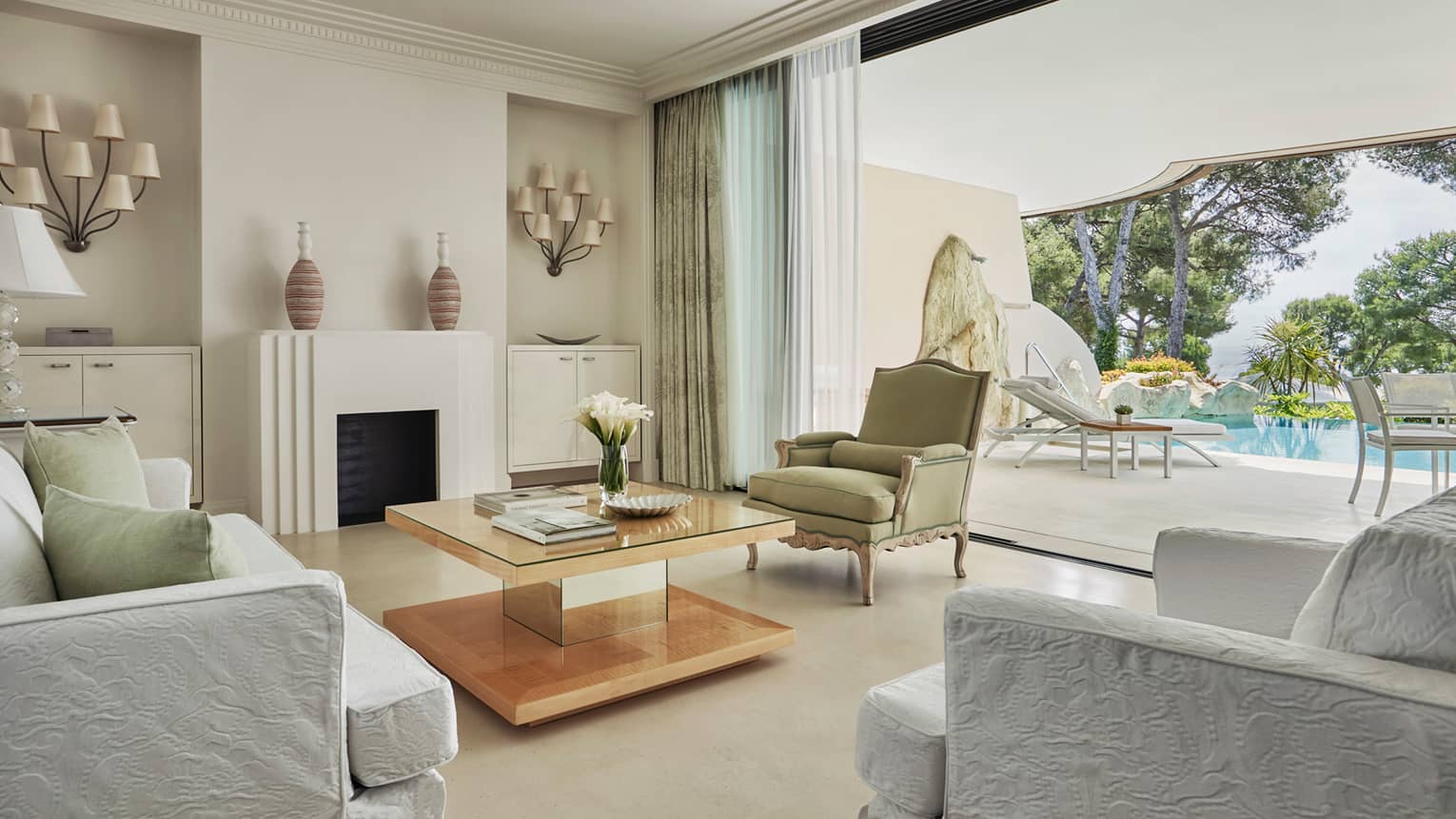 Pool Suite open-air living room with crisp white decor leading to sunny patio, pool