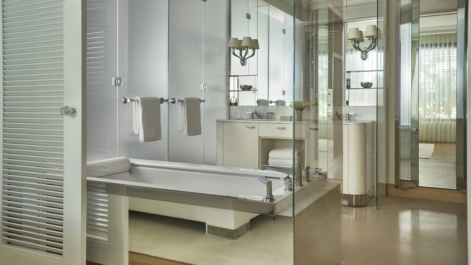 Hotel suite all-white bathroom with deep soaking tub and double vanity