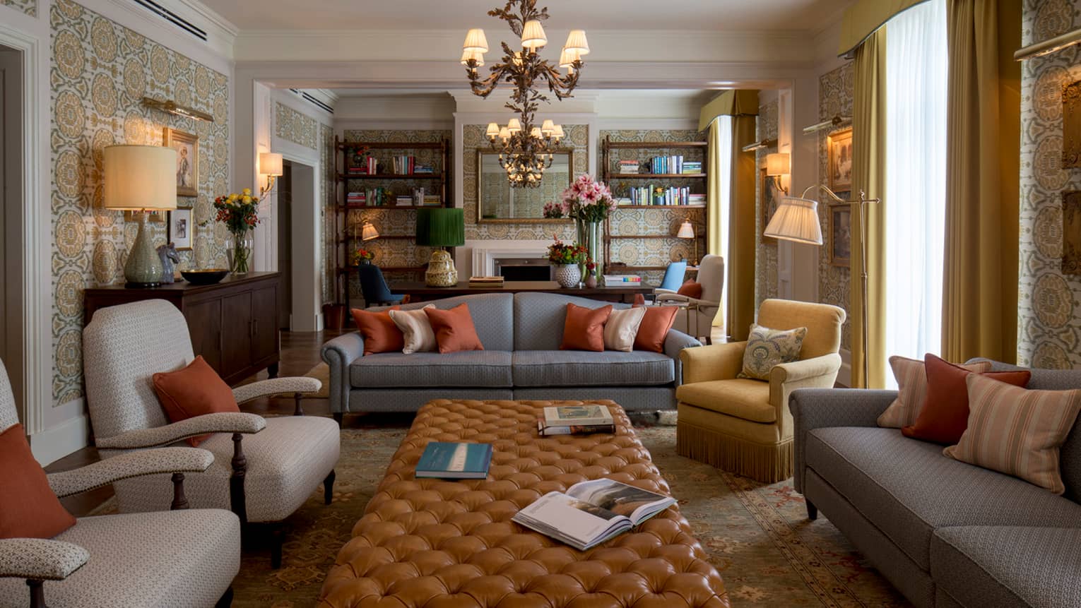 Royal Suite sofas, chairs around long tufted leather bench under chandeliers, bookshelves