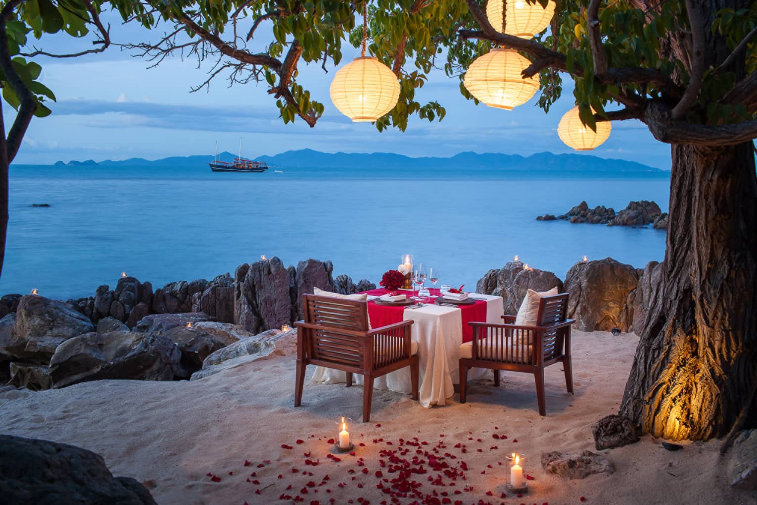 Private dining setting on the beach with a view of the Gulf of Thailand