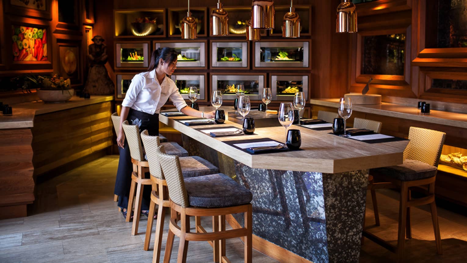 Hotel staff sets glass on stone and wood private dining meeting table