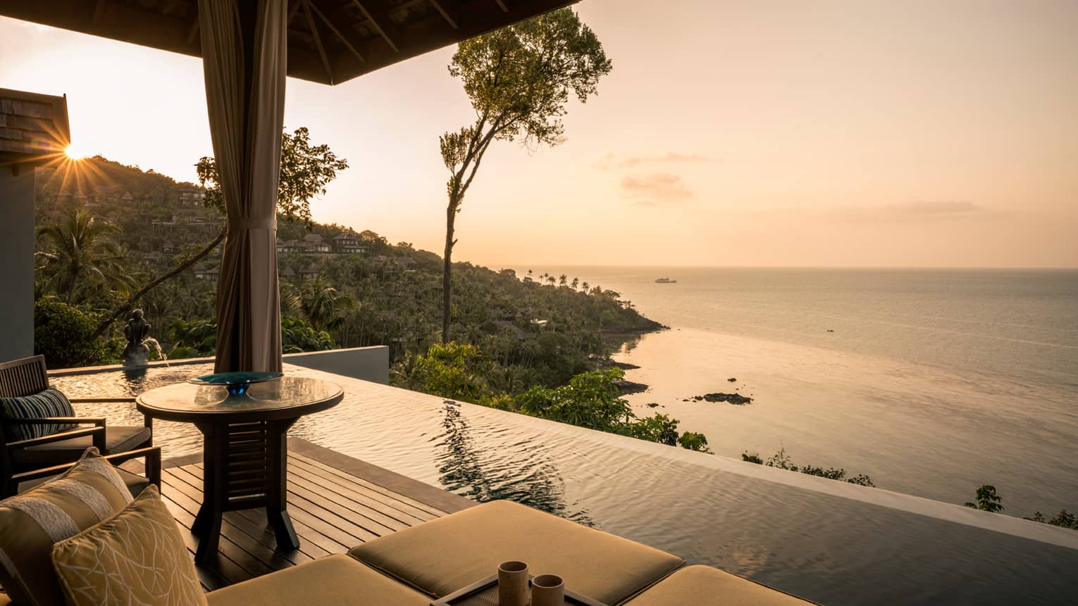 One-bedroom pool villa patio chair, infinity pool overlooking mountain, ocean at sunset