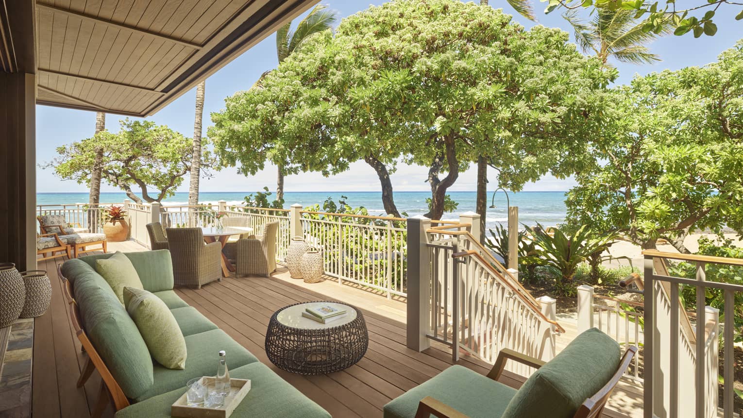 Kailani Suite balcony with mint green couch and arm chair, rattan coffee table, ocean views