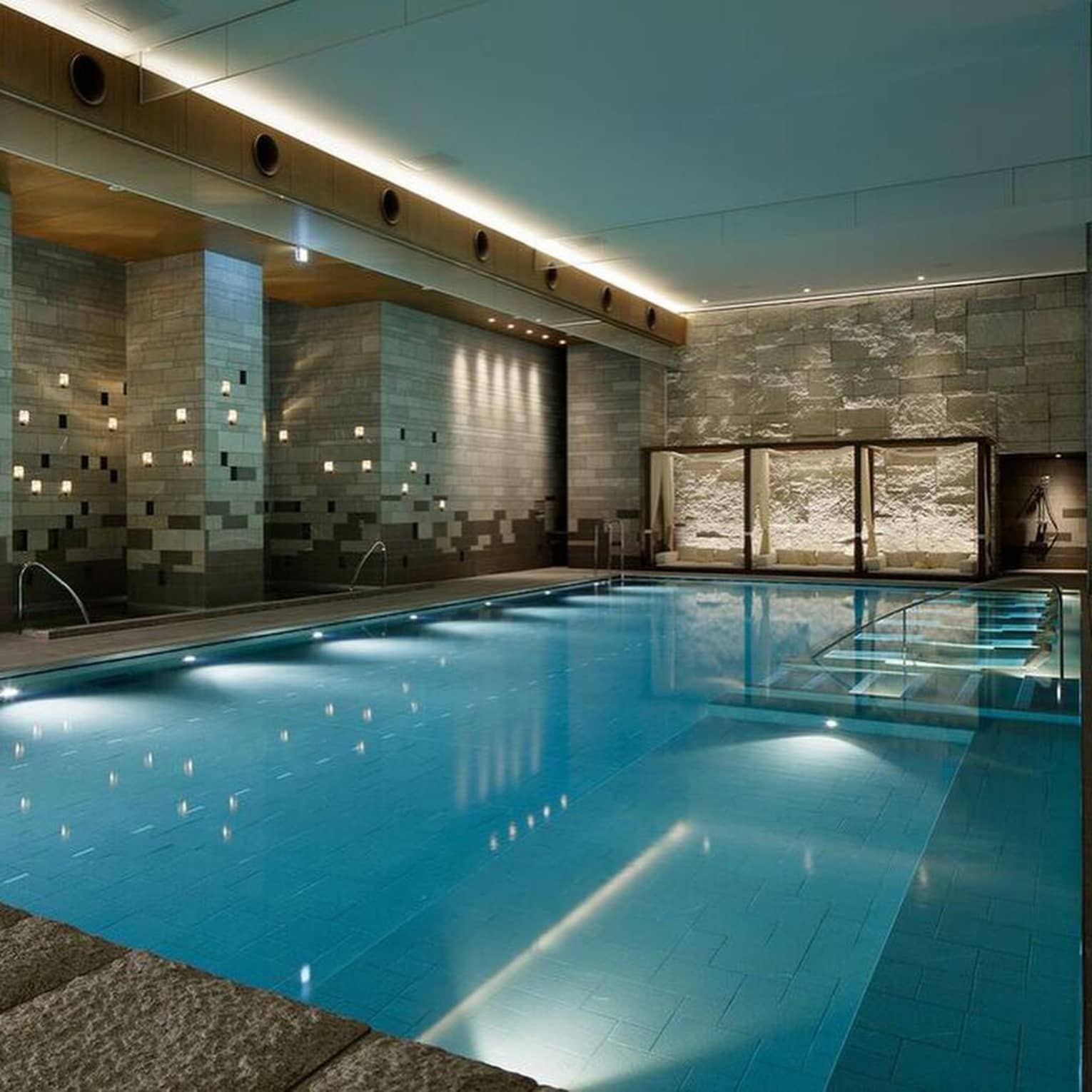 Indoor swimming pool with modern stone walls and ambient lighting at Four Seasons