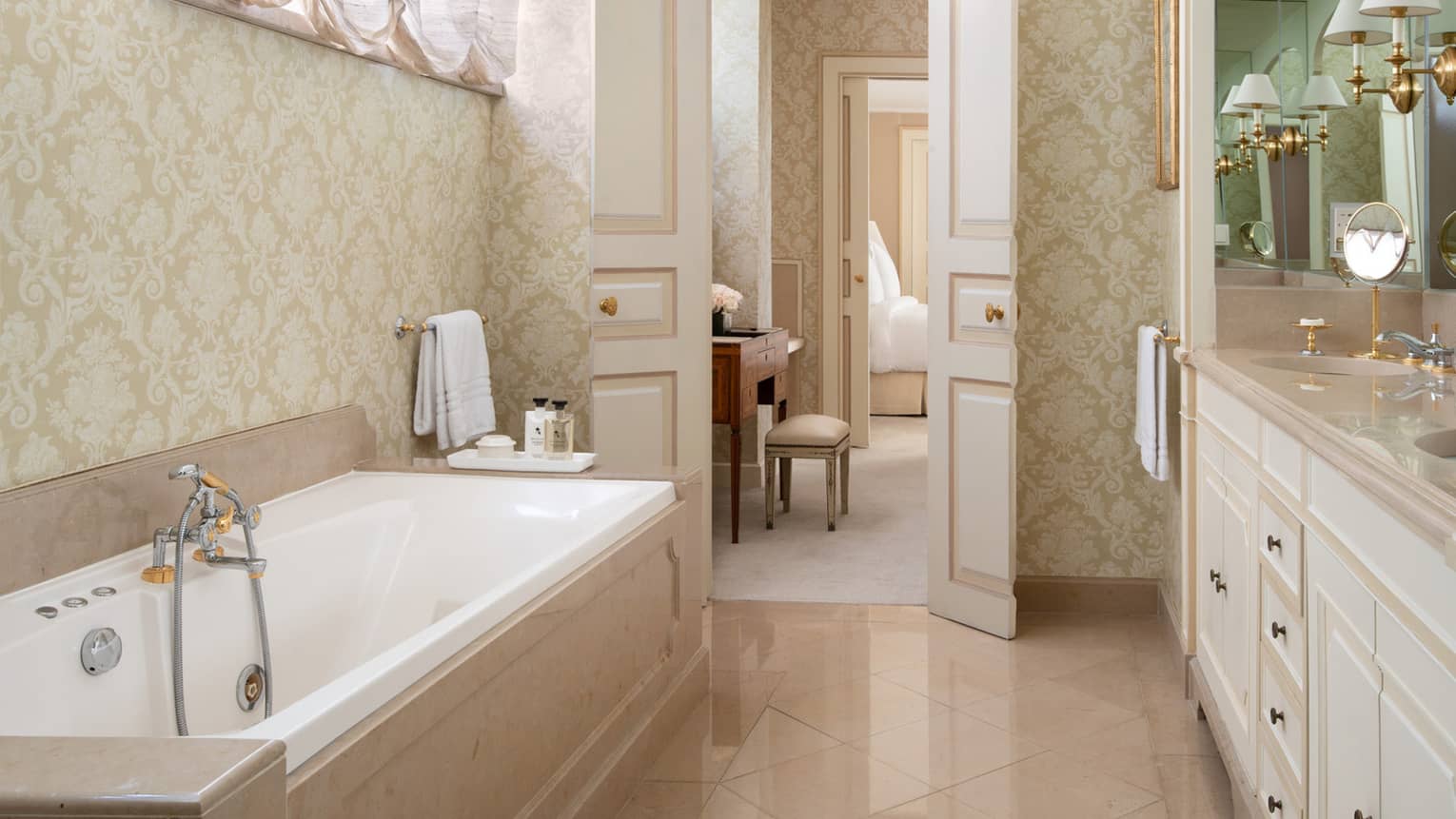 Long, narrow neutral bathroom with large tub,  and vanity, view through door to vanity