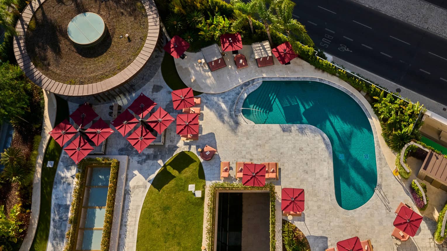 Aerial view of kidney-shaped pool surrounded by red umbrellas