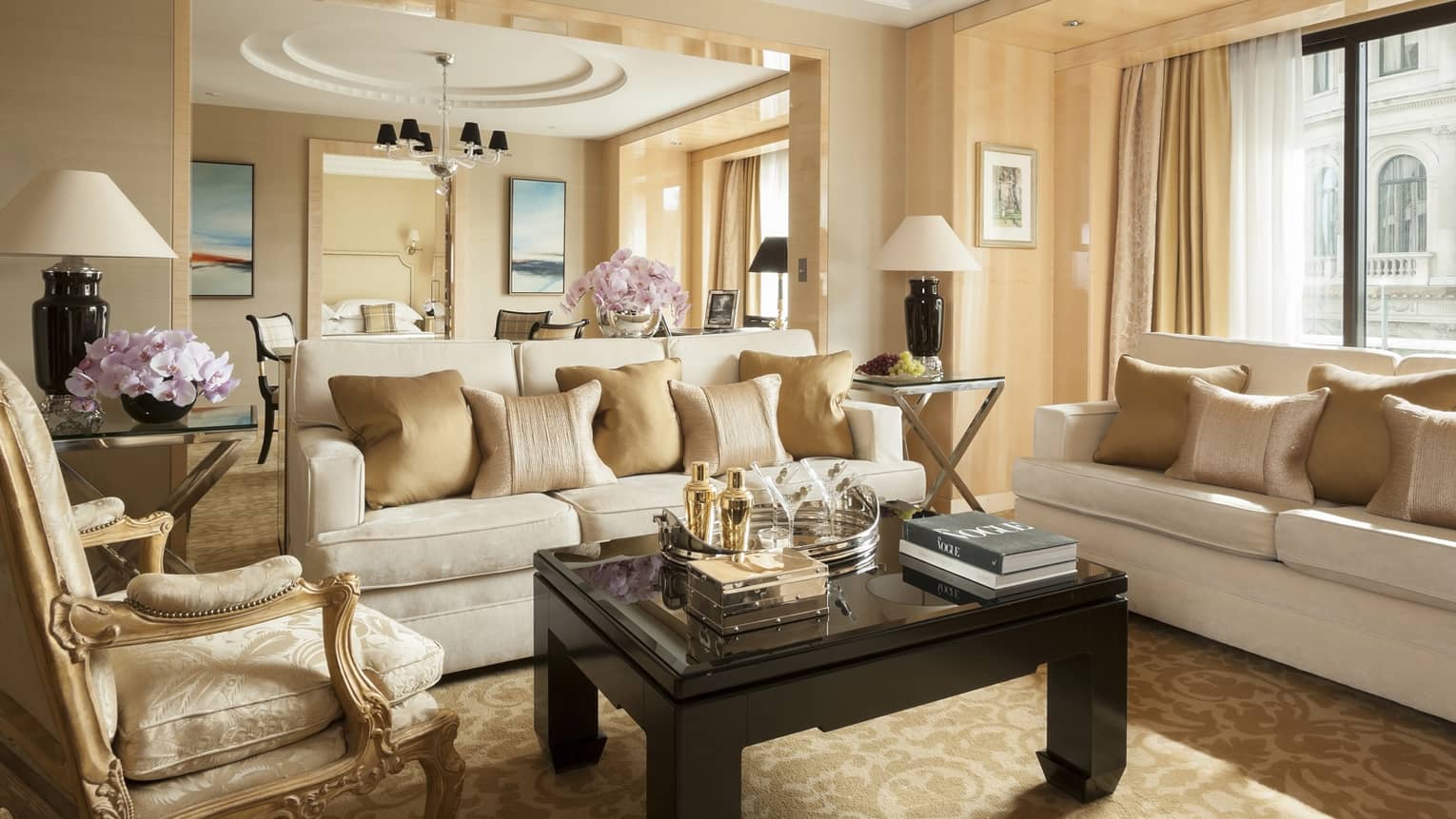 Grand One-Bedroom Suite elegant sofas, gold accent chairs under tall ceilings, dining room in background