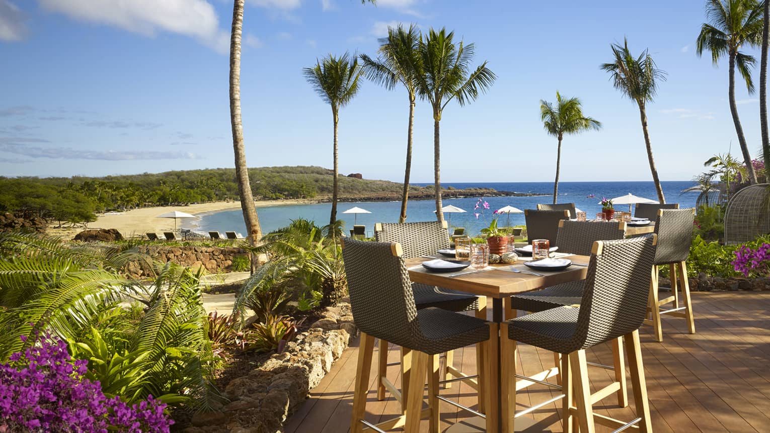 Malibu Farm Bar dining table, chairs on sunny patio overlooking beach, ocean