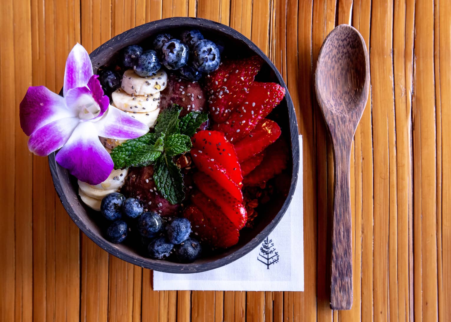 Acai bowl with strawberries, blueberries and a Hawaiian flower