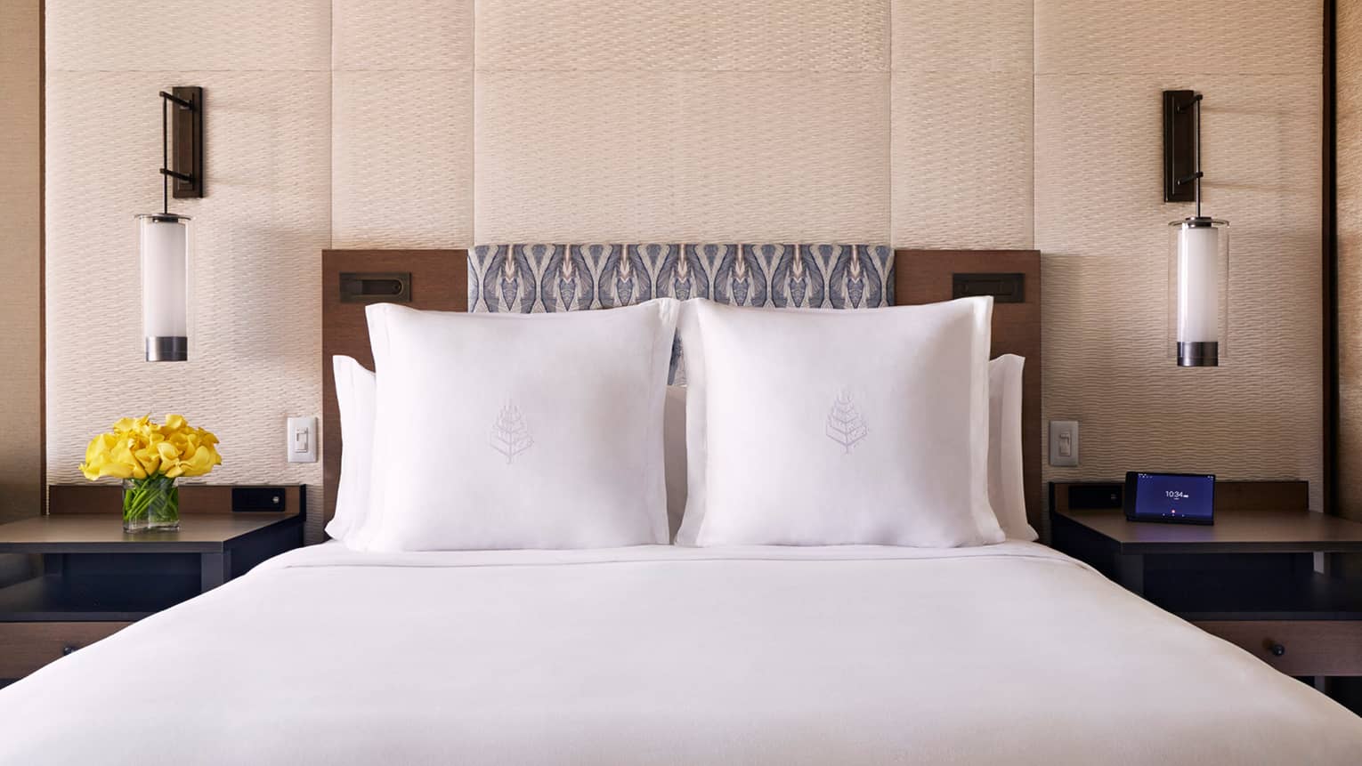 Partial Ocean-View room bed with white pillows with Four Seasons logo, wood headboard, wall panel