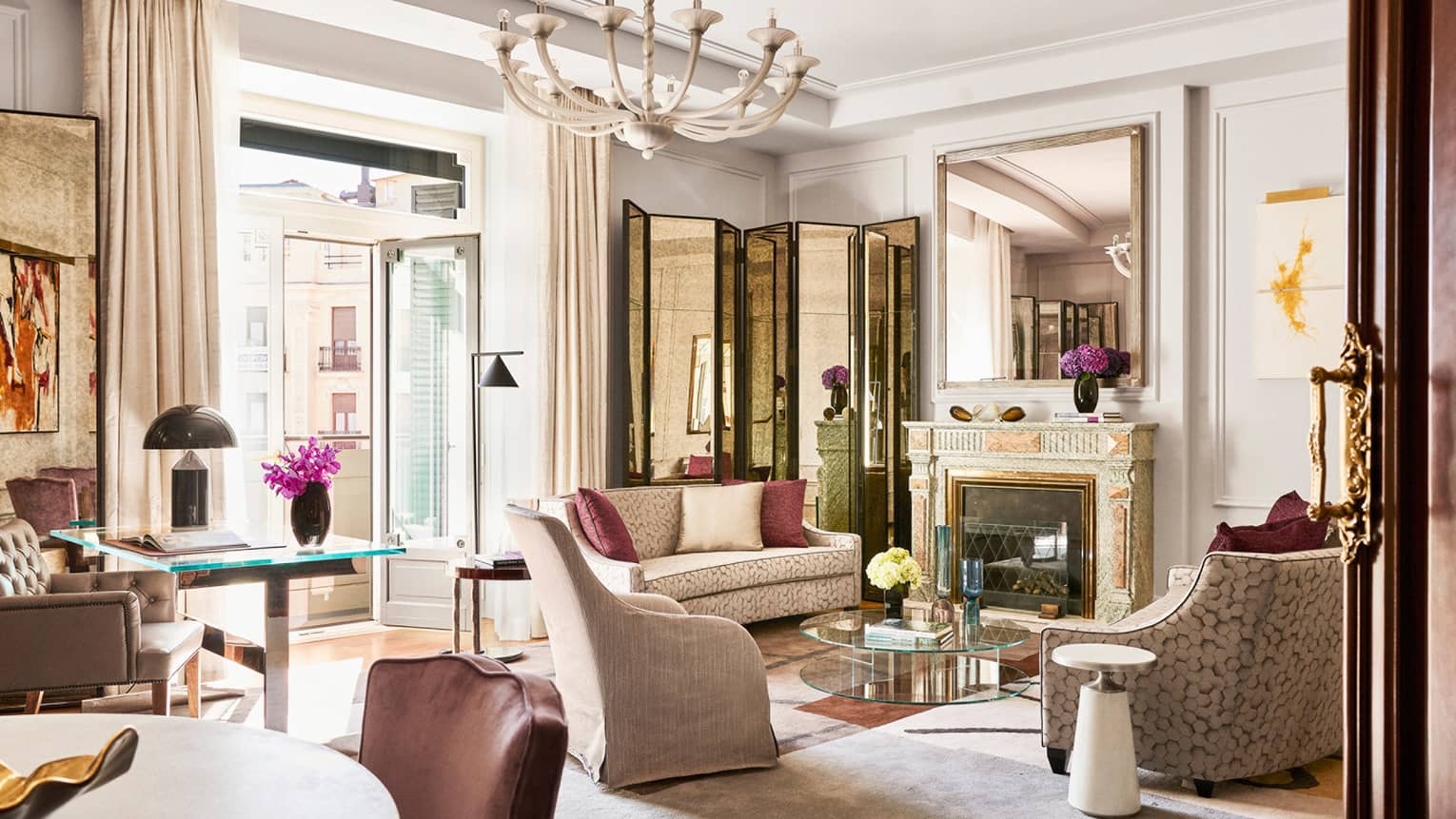 Ornate living room with chandelier, two two-person sofas, arm chair, glass doors to terrace