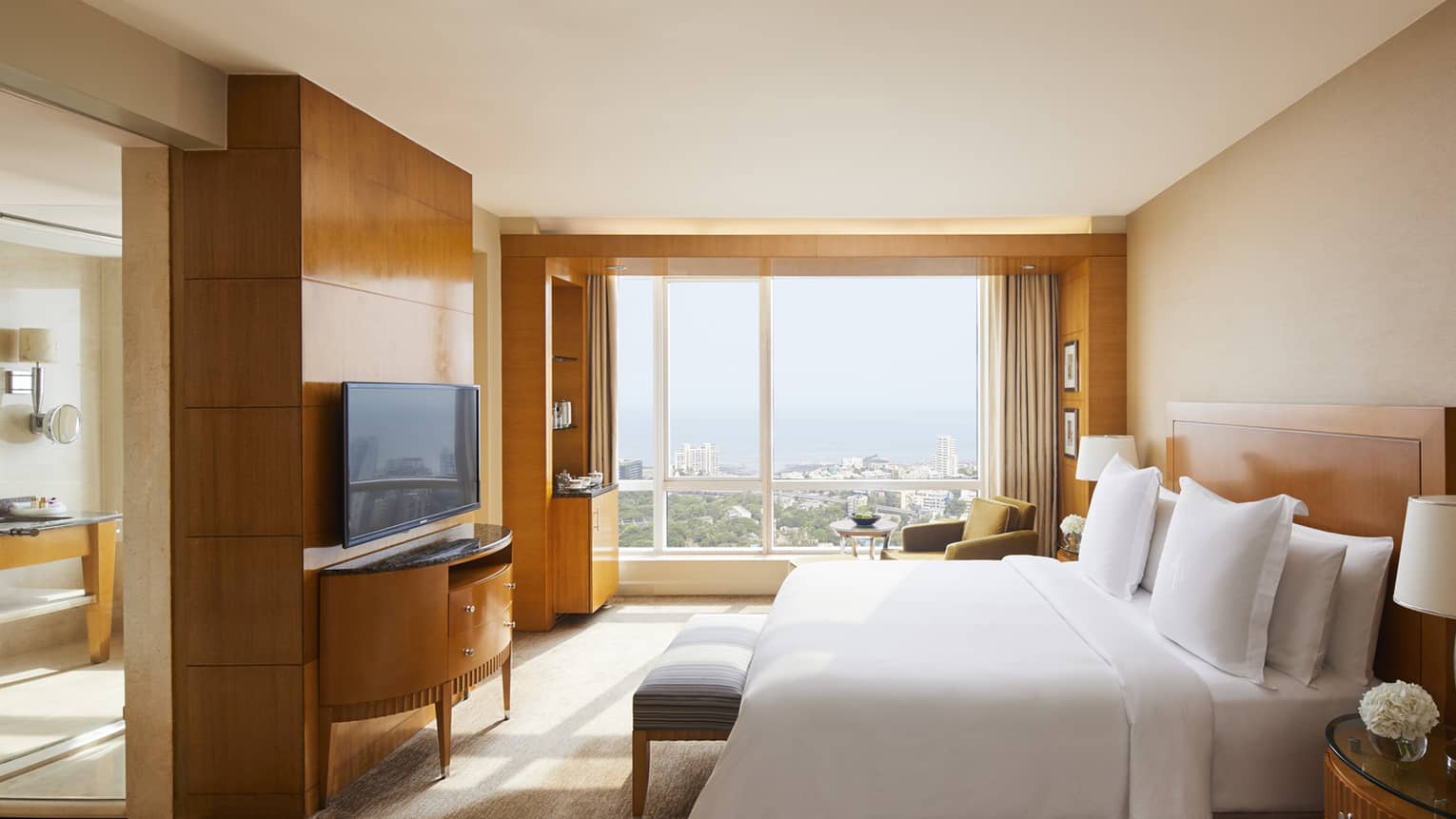 Deluxe room with natural light coming in and a view of the Mumbai skyline