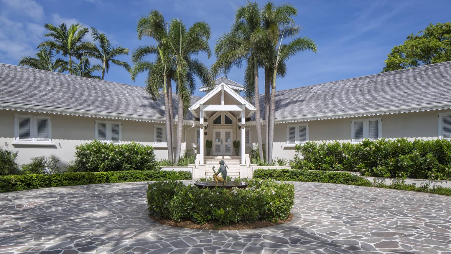 Exterior of villa at Four Seasons Nevis, with cobble-stone driveway and palm trees