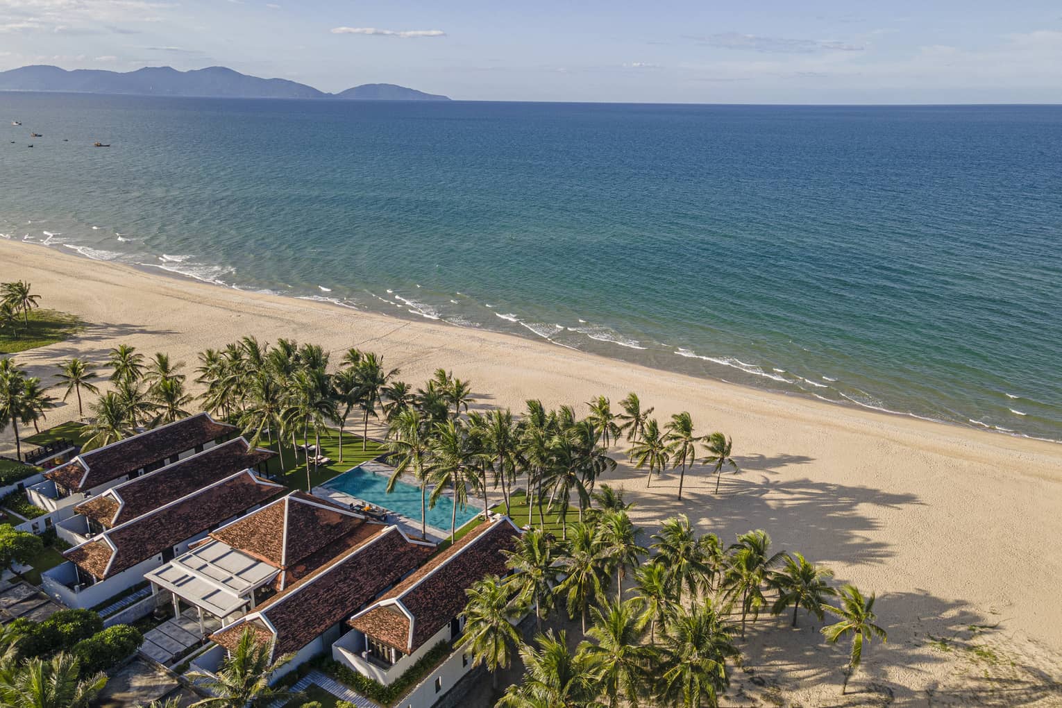 5 Bedroom Beachfront Pool Villa aerial shot with ocean and mountain views, palm trees and blue skies