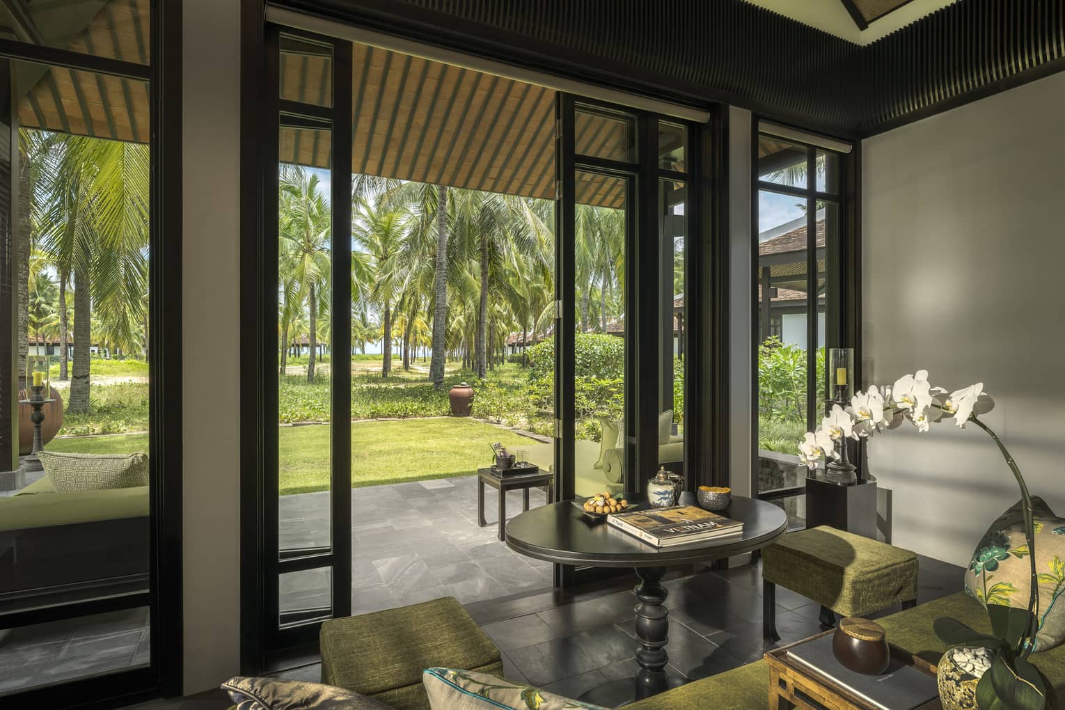 Family Villa living area opening on stone floor veranda with palm tree views