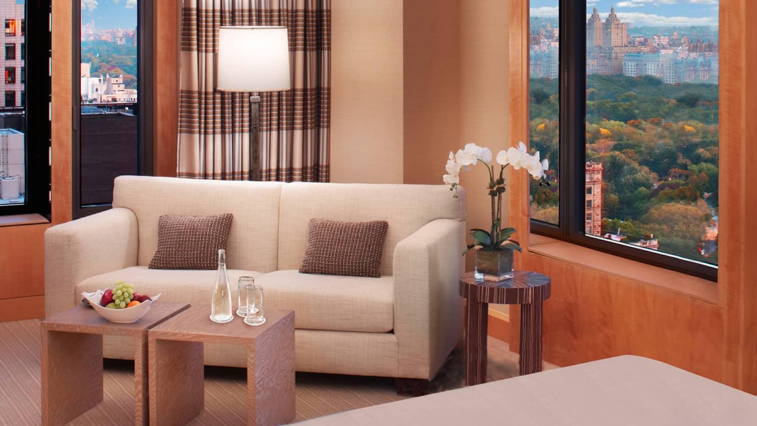 Corner suite with white loveseat sofa, small modern tables with fresh fruit, water, white orchid