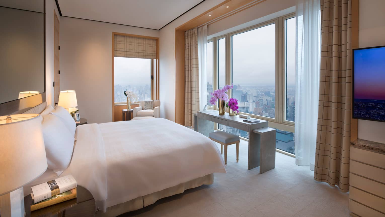 Presidential Suite side of bed in front of grey console table, small stool, purple orchids, window