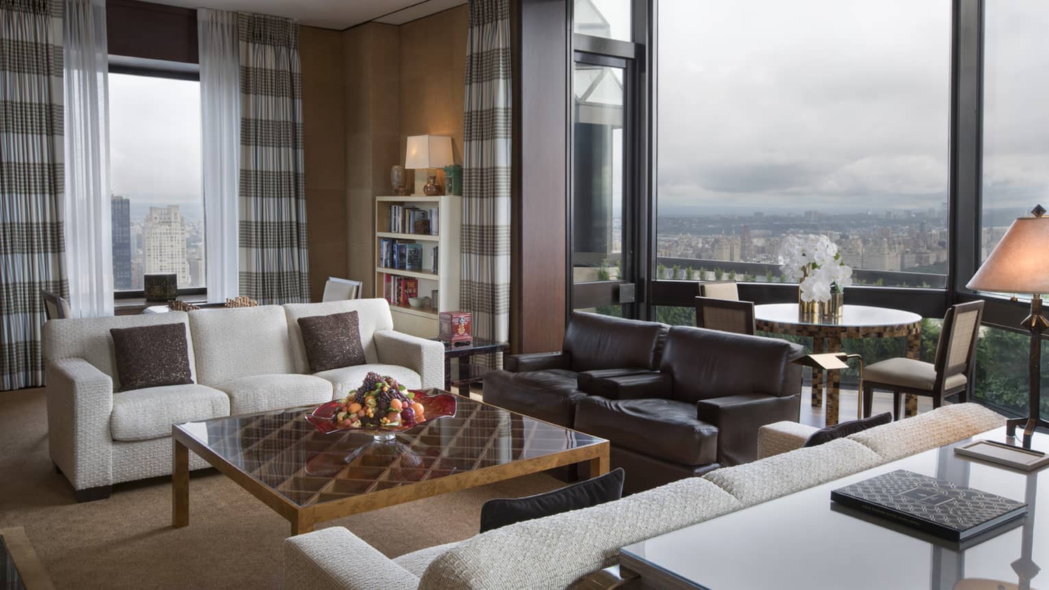 Presidential Suite living room with two sofas, armchairs, small dining table in glass alcove