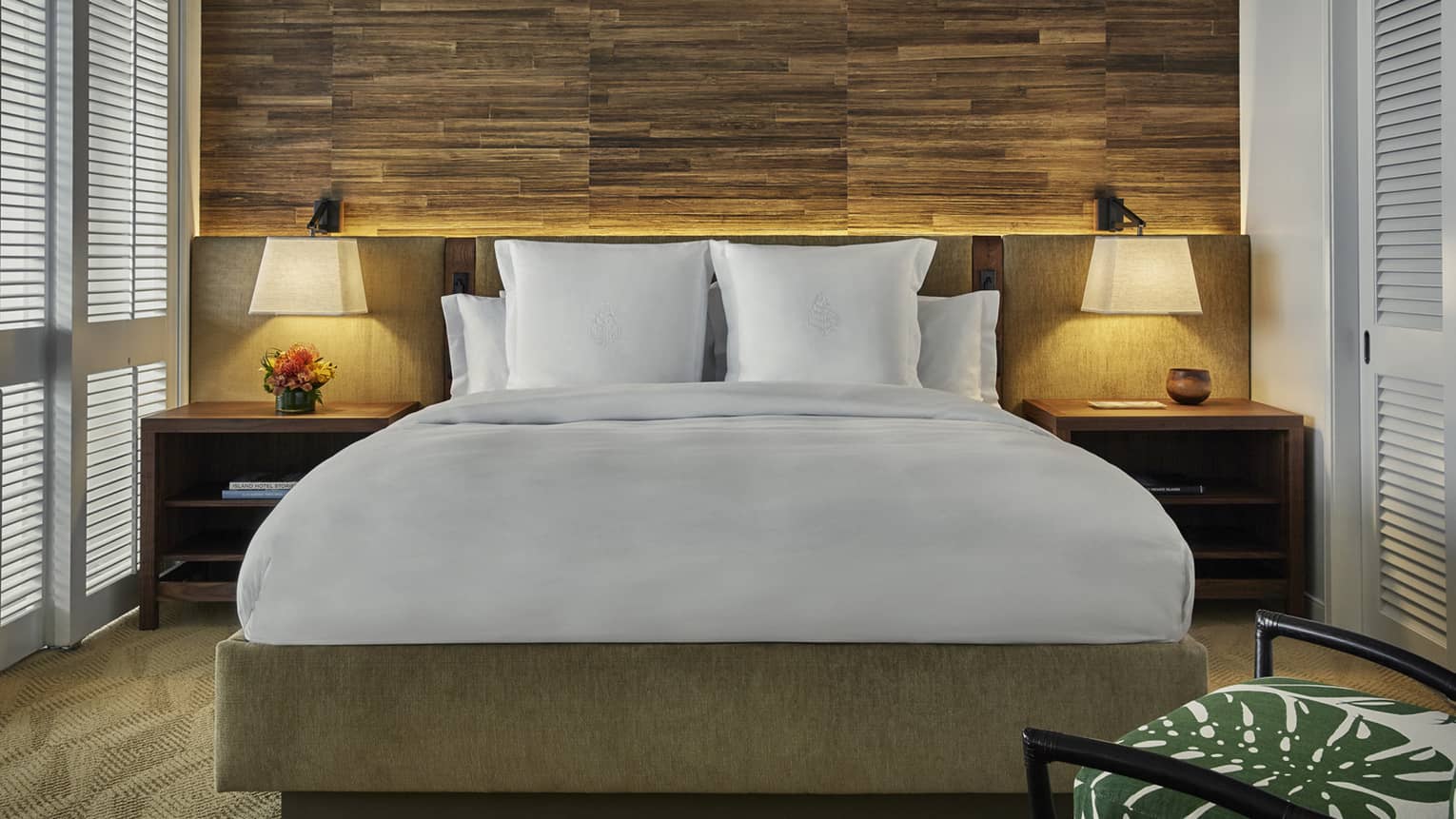 Bed with retro-style wood and upholstered headboard, nightstands, lamps, rustic wood wall