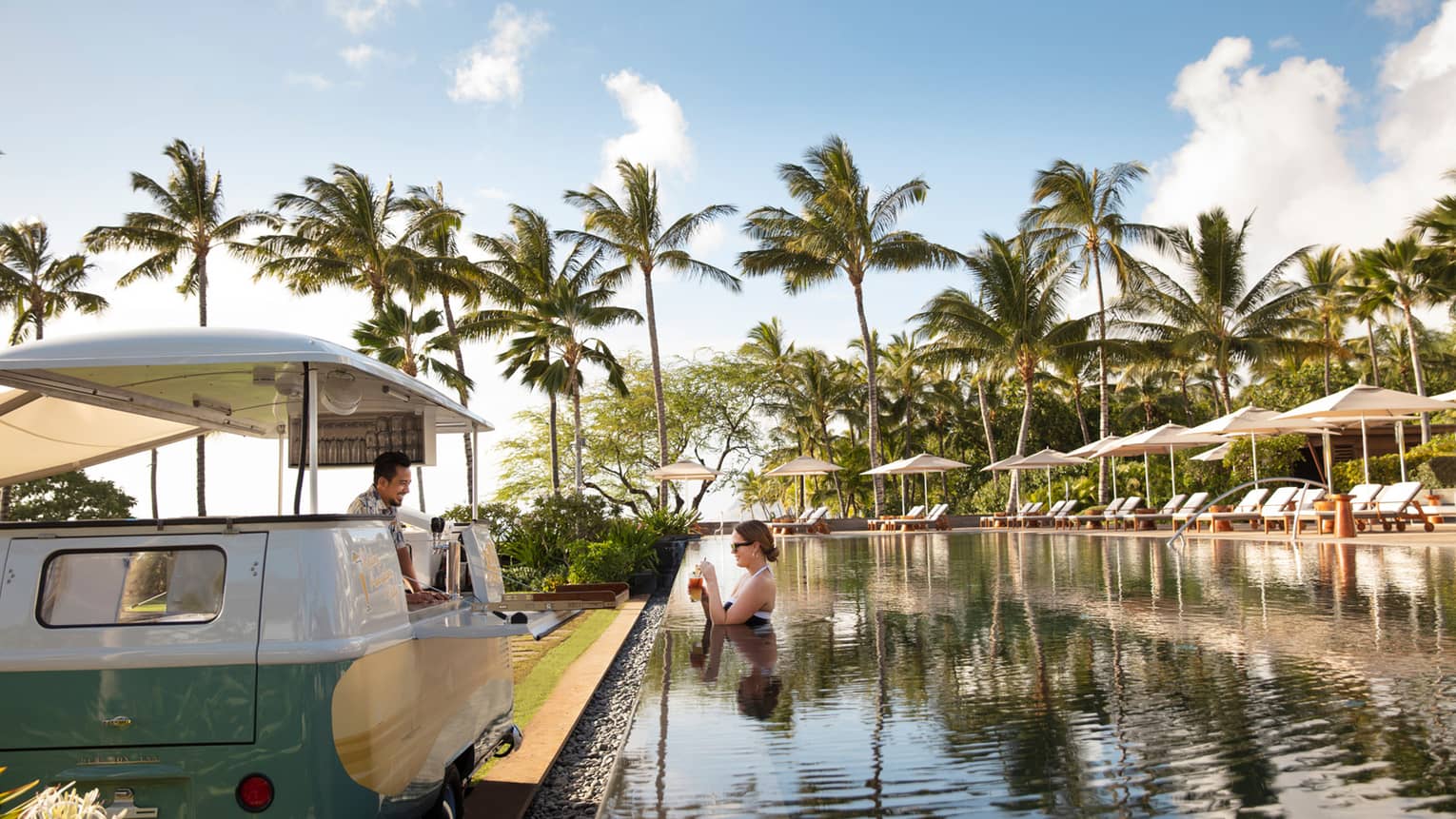 A woman orders a drink from Dr. Mai Tai's swim-up bar at the Four Seasons Resort Oahu infinity pool