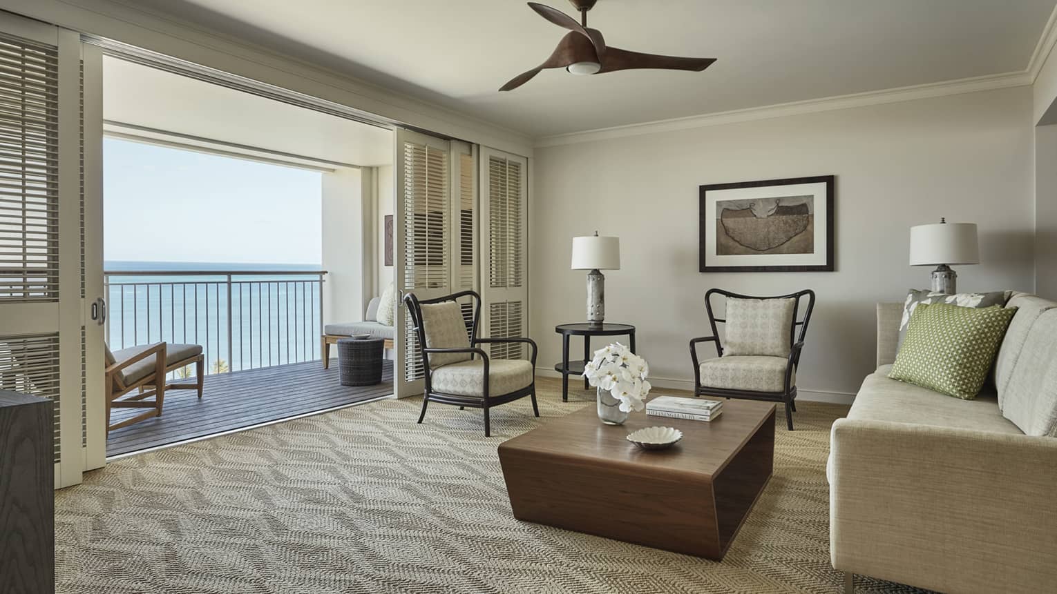 Oceanfront Suite chairs, wood table, sofa facing open wall, sliding shutters, balcony