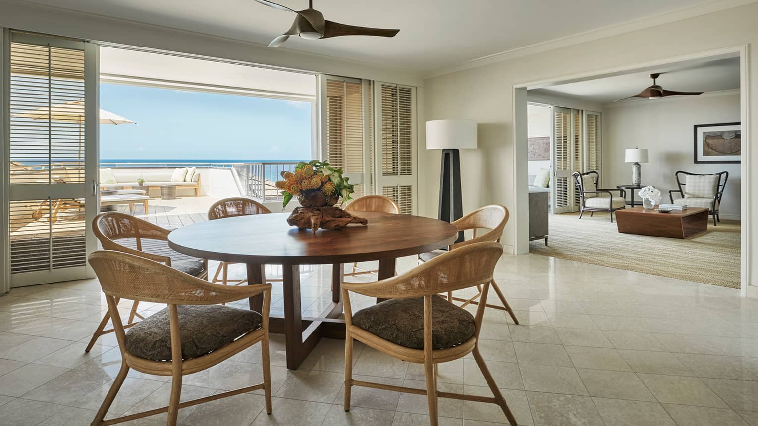 Residence dining room with round wood table retro wicker seats, sliding balcony shutters