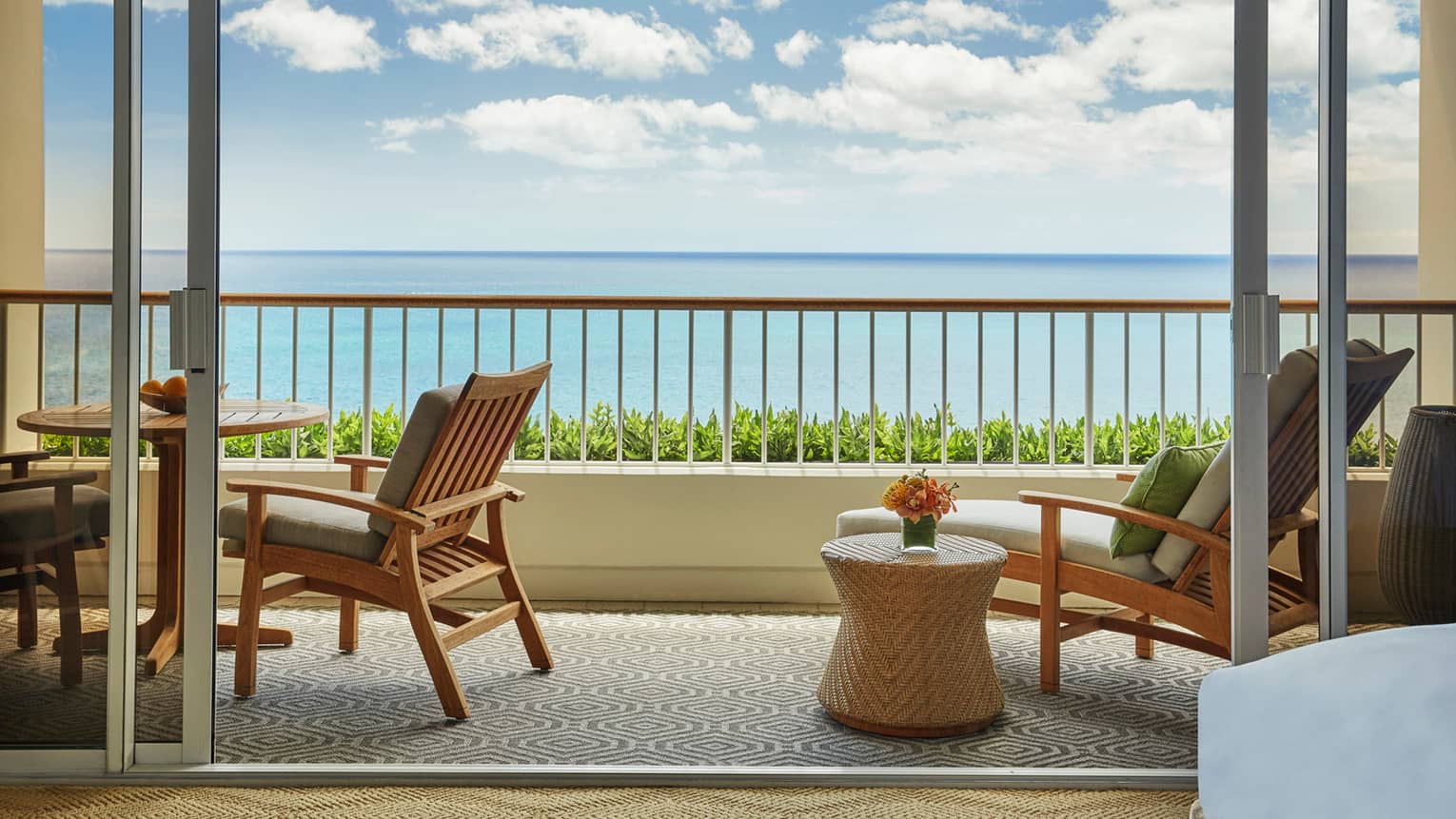 Junior Suite balcony with wood and wicker lounge furniture, ocean views 