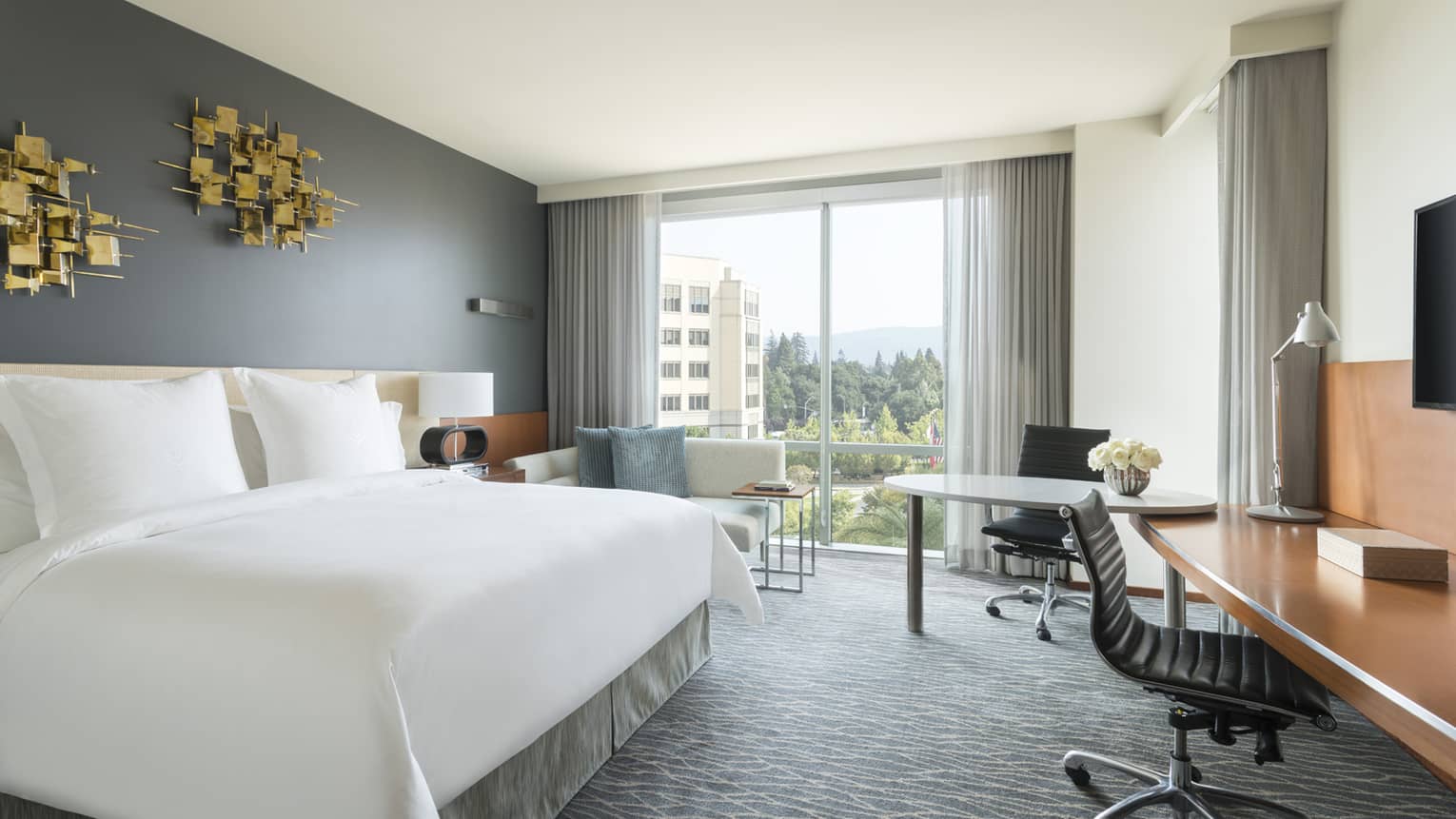 Premier Room bed under modern gold art, two desks, chaise by floor-to-ceiling window