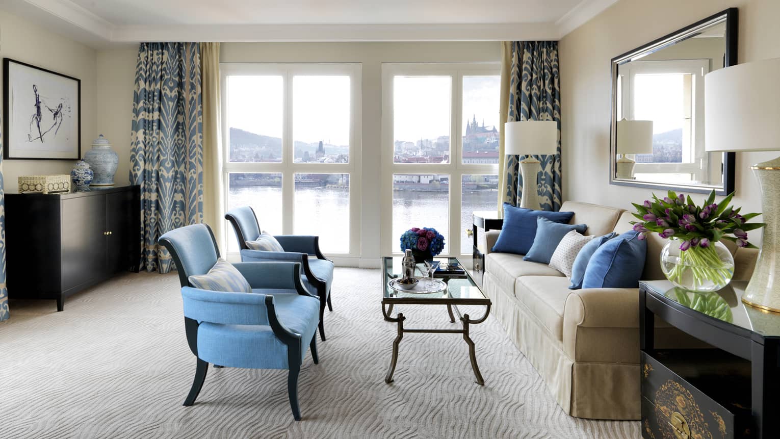 River Suite with two blue armchairs in front of glass coffee table, sofa, floor-to-ceiling windows with Vltava River view