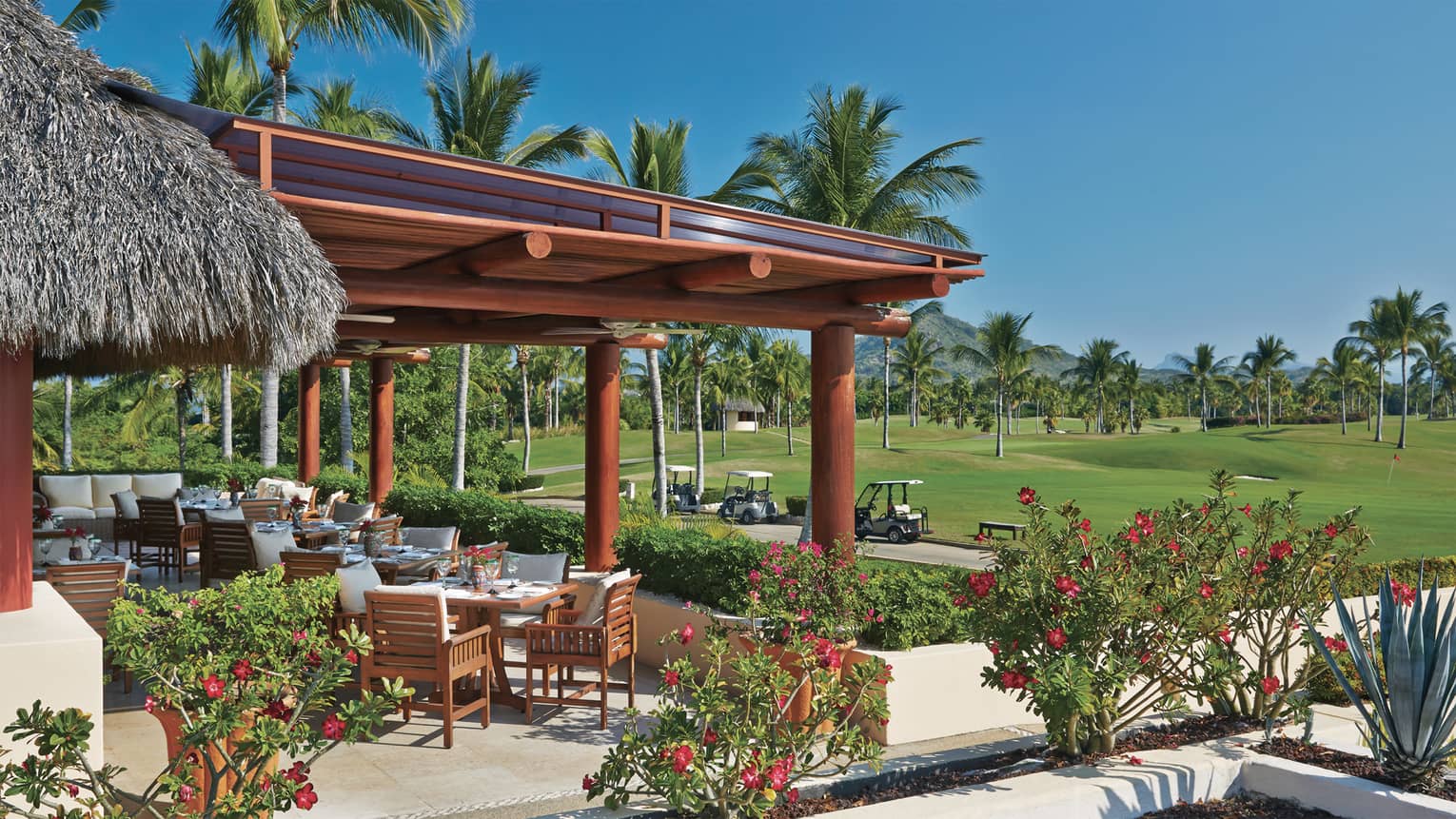 Tail of the Whale patio dining lounge under large wood awning, next to path with white golf carts