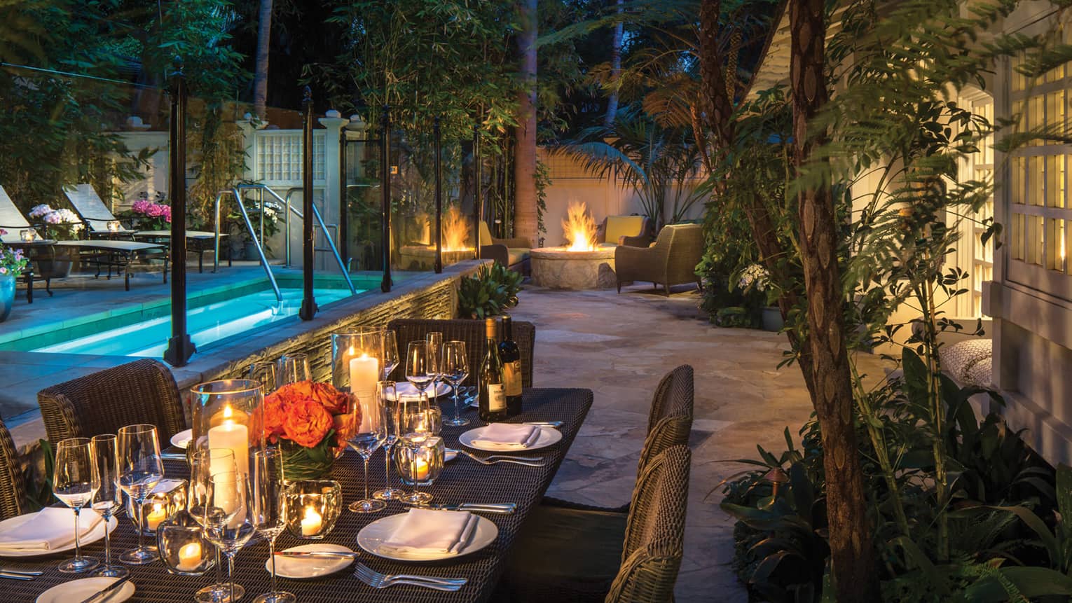 Ty Warner bungalow backyard candle-lit patio dining table by plunge pool, fire pit at night