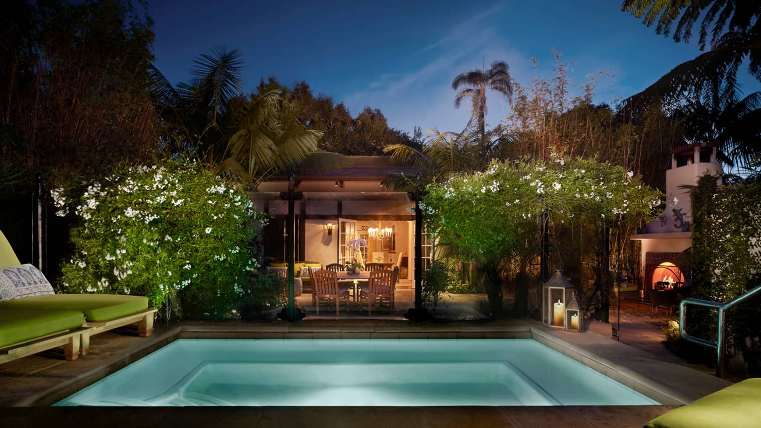 Bungalow Suite backyard at night with illuminated plunge pool, tropical plants, lights from living, dining room