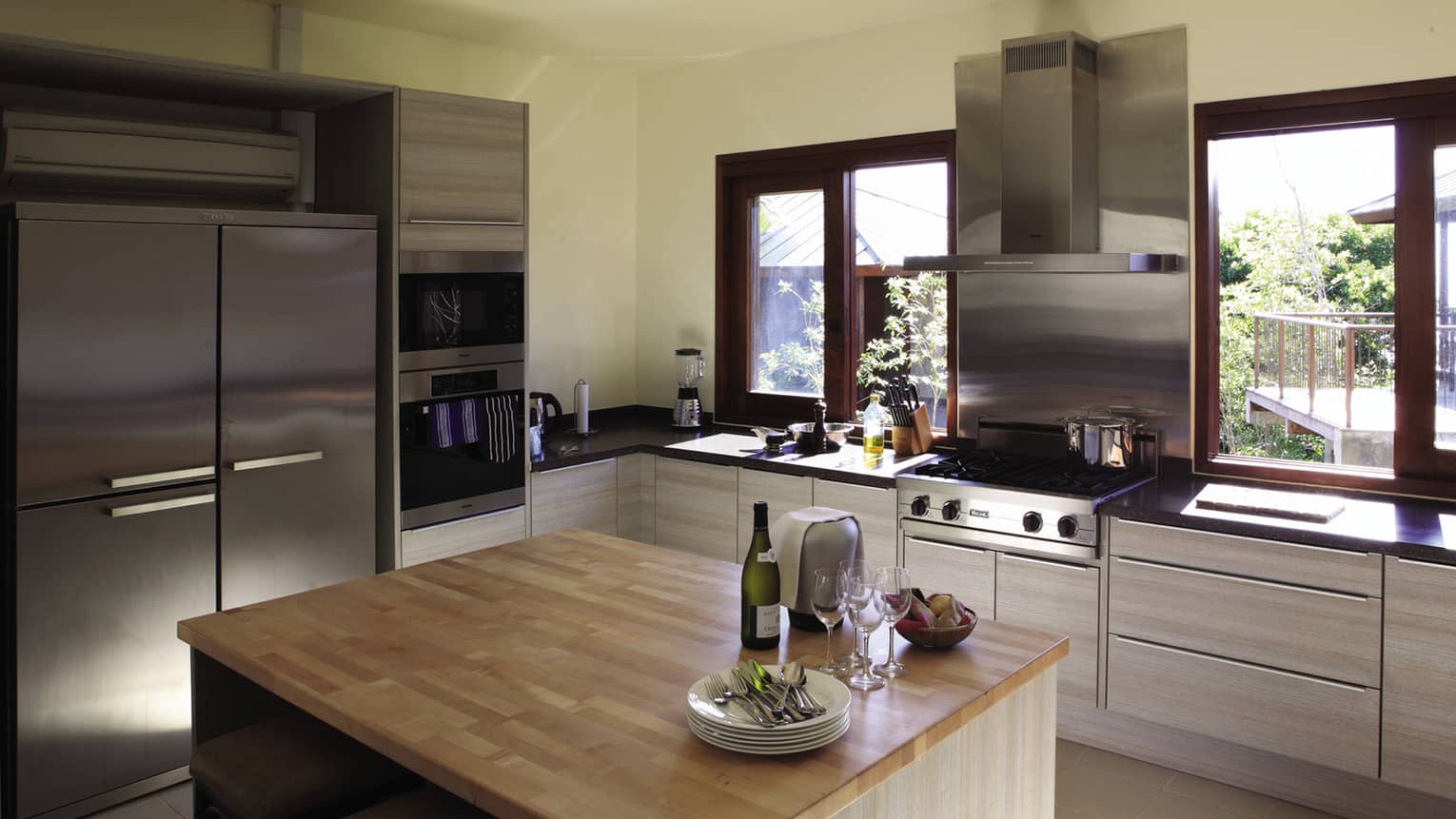 Champagne bottle, glasses, stack of plates on butcher block island in modern kitchen