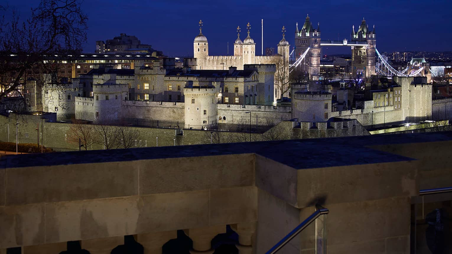 View over wall to Tower Bridge and the Tower of London at night