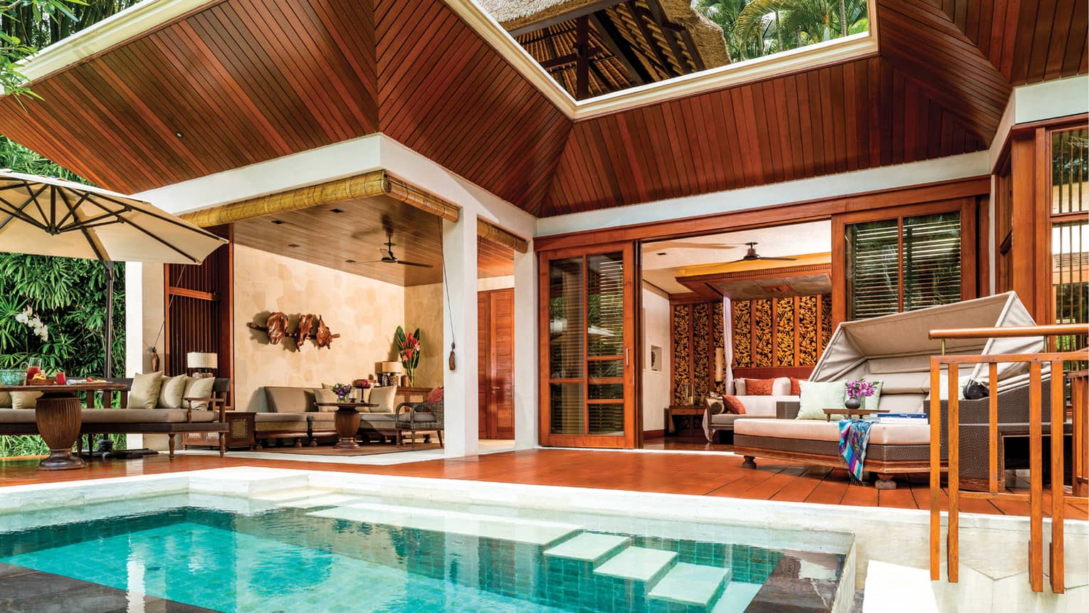 Small rectangular plunge pool in front of wood patio with beige sofas and dining chairs, wood villa roof