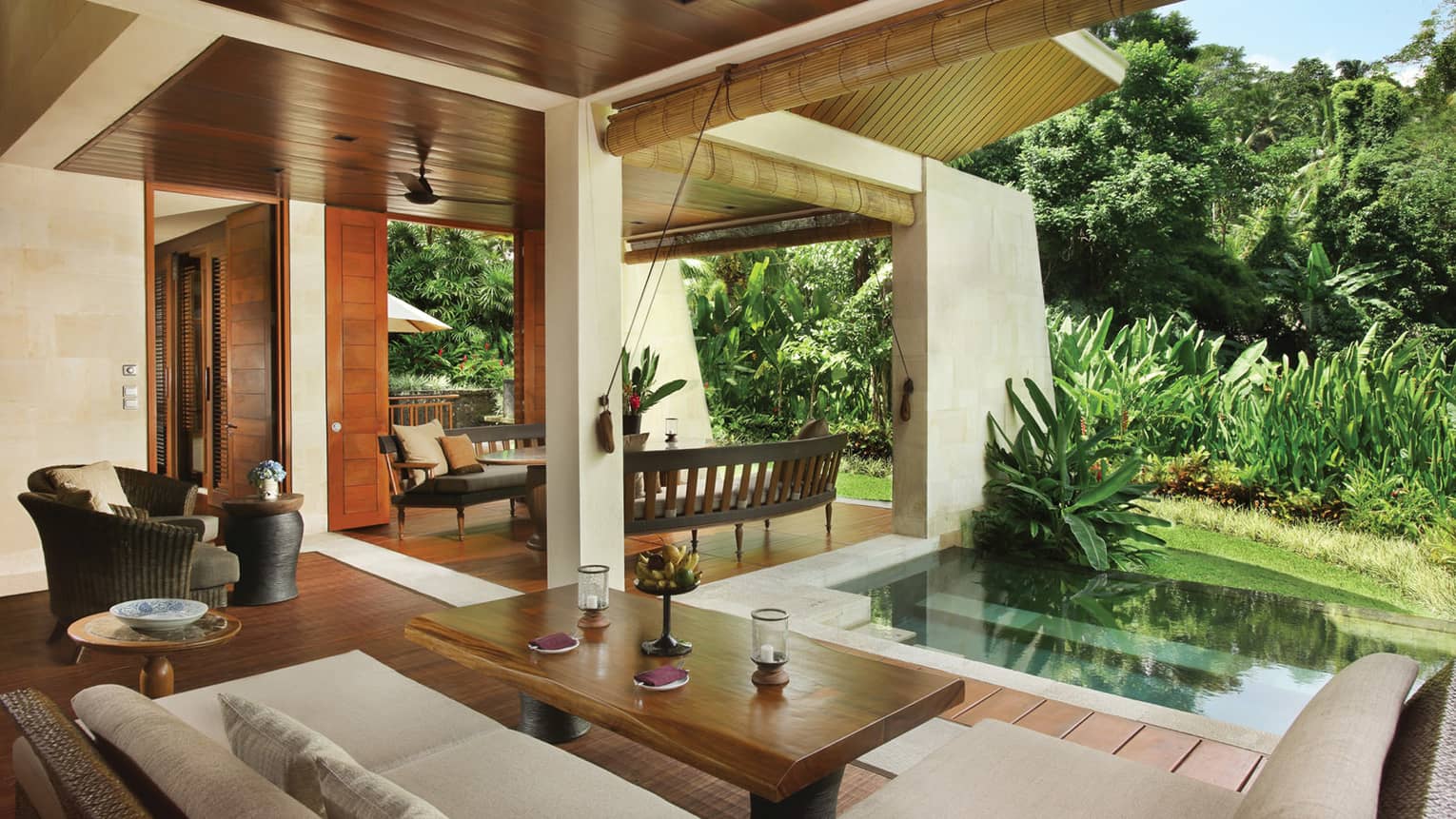 Two Bedroom Villa open-air living space with wood floors, white patio sofa, plunge pool beside green tropical plants