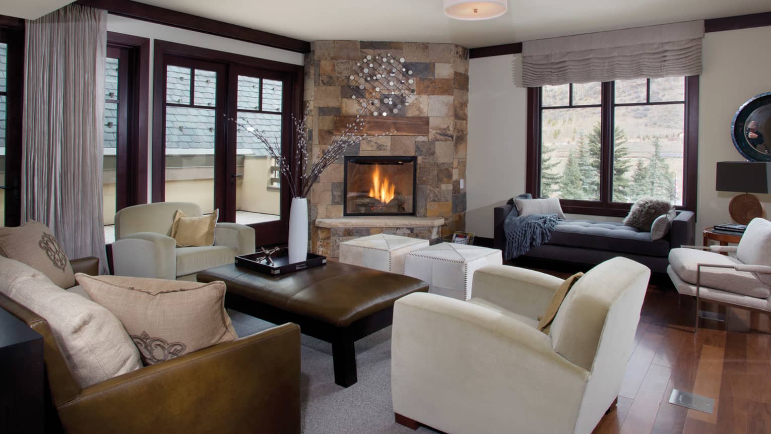 Two-bedroom residence suite living area with leather sofa and coffee table, window chaise, stone fireplace
