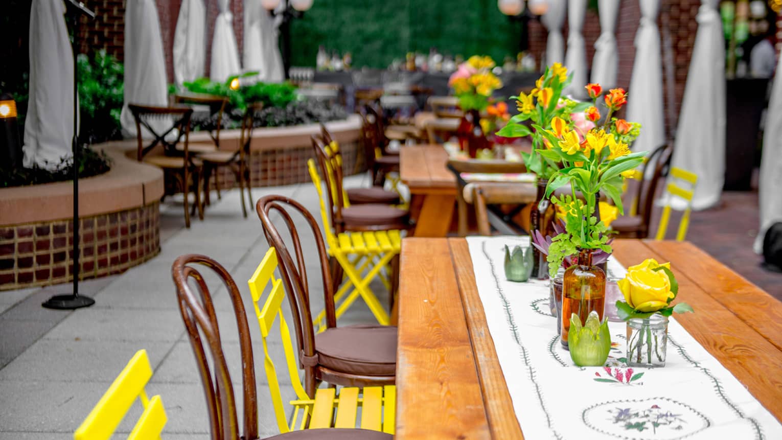 Colourful flowers, chairs, linens around outdoor patio dining tables 