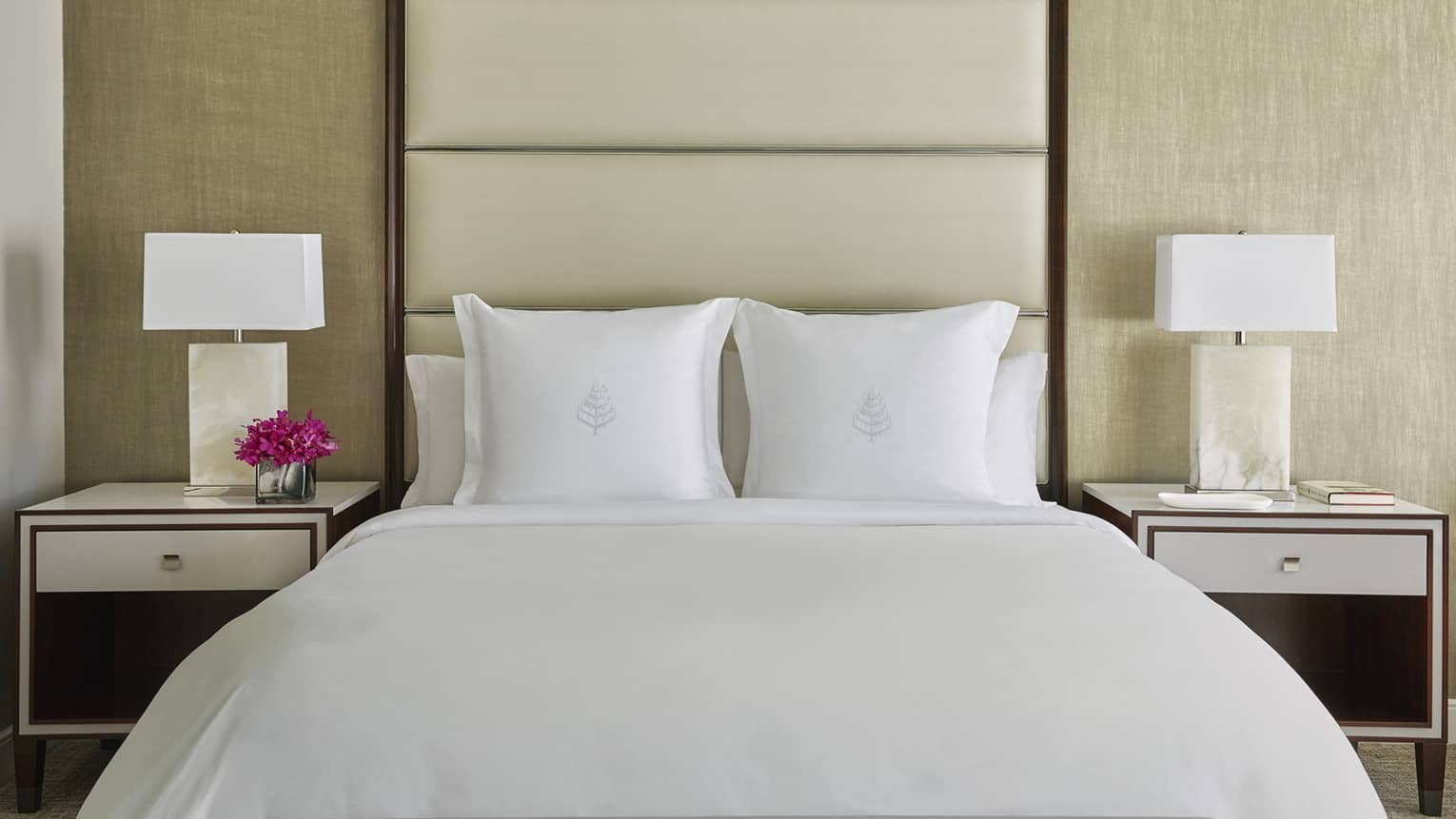 Deluxe Accessible Room head-on view of bed with white linens, tall padded beige headboard, nightstands with lamps