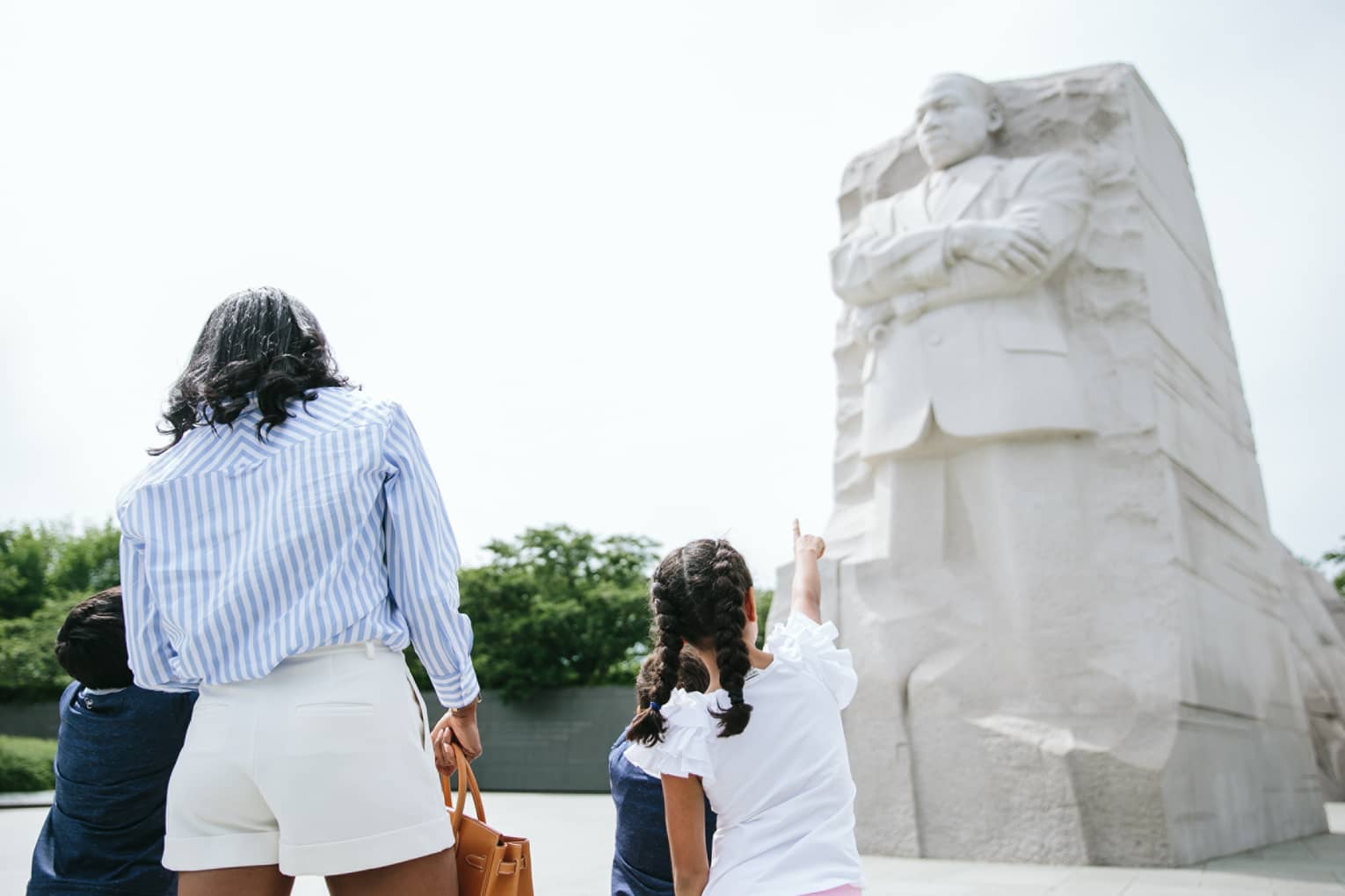 A woman and three children looking at the Martin Luther King, Jr. Memorial on a sunny day.