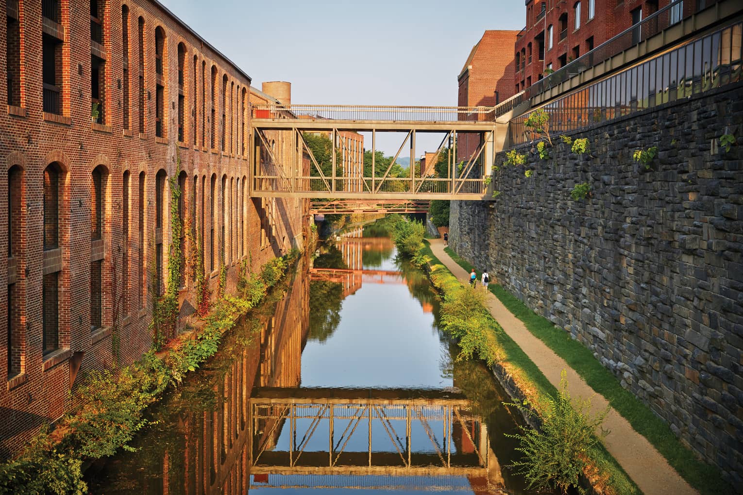 A canal between a stone wall and brick building.